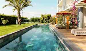 Pitkä ja kapea uima-allas ympäröitynä viheralueilla ja modernilla asumisella. (Tekoälyn luoma teksti)