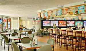 Ravintolan sisätila, jossa pöytiä, tuoleja ja baaritiski korkeine tuoleineen. (Tekoälyn luoma teksti)