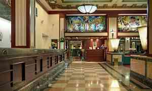 Sisäänkäyntiaula, jossa on marmorilattia, vastaanottotiski ja koristeellinen sisäkatto. (Tekoälyn luoma teksti)