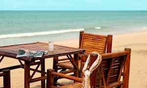 Puuinen tuoli ja pöytä rannalla merimaisemassa. (Tekoälyn luoma teksti)