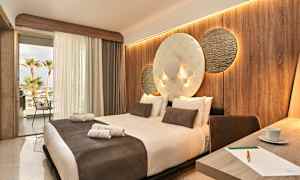 Hotellihuone, jossa on suuri sänky, koristelu seinä ja avoin parveke näkymällä. (Tekoälyn luoma teksti)