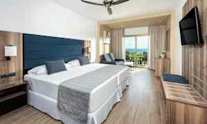 Hotellihuone kahdella yhden hengen vuoteella, oleskelualueella ja parvekkeella. (Tekoälyn luoma teksti)