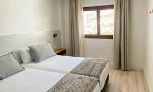 Hotellihuone, jossa kaksi erillistä vuodetta, ikkuna valon sisääntulon kanssa ja osa näkymästä ulkona. (Tekoälyn luoma teksti)