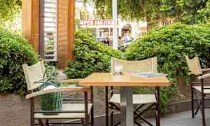 Ulkomiljöössä pöytä ja tuoleja kasvillisuuden vieressä. (Tekoälyn luoma teksti)