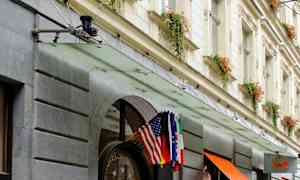 Hotellin julkisivu, sisäänkäynti koristeltu kukkaruukuilla ja lipuilla. (Tekoälyn luoma teksti)