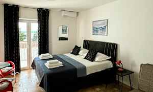 Makuuhuone, jossa on parivuode, istuimet ja lasiovi parvekkeelle. (Tekoälyn luoma teksti)