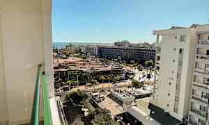 Näkymä parvekkeelta kaupungin yli, taustalla meri ja aurinkoinen sää. (Tekoälyn luoma teksti)