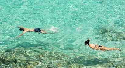 Kaksi henkilöä snorklaa kirkkaassa turkoosissa vedessä. (Tekoälyn luoma teksti)