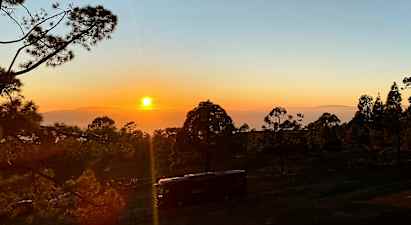 Kuva auringonlaskusta metsän yllä, etualalla yksi ajoneuvo. (Tekoälyn luoma teksti)