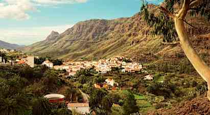 Vuoristokylä, jossa on valkoisia taloja ja punaisia kattoja, sijaitsee vihreässä laaksossa korkeiden vuorten ympäröimänä. (Tekoälyn luoma teksti)