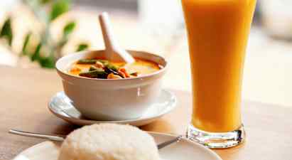 Kulho keltaista currya, lautanen riisiä ja lasi keltaista juomaa. (Tekoälyn luoma teksti)