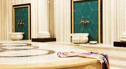 Kuva perinteisestä hamamista, jossa on marmoria ja vesihanoja. (Tekoälyn luoma teksti)