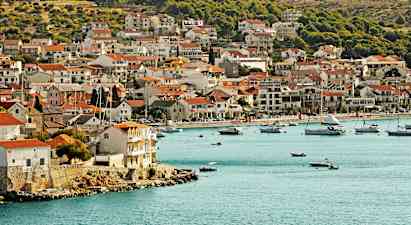 Rannikkokaupunki, jossa taloja lähellä vedenrantaa ja veneitä lahdella. (Tekoälyn luoma teksti)