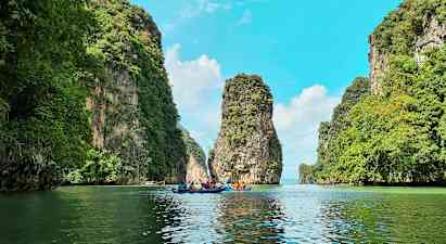 Useat henkilöt melovat kajakkeja kauniin maiseman läpi, korkeiden vihreiden kallioiden välissä. (Tekoälyn luoma teksti)