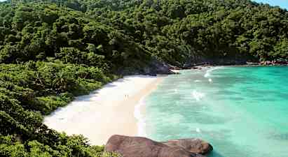 Kuva rannasta, jota ympäröivät vihreät vuoret ja sininen meri. (Tekoälyn luoma teksti)