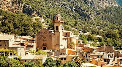 Kivikirkko tornilla, jota ympäröi kylä vuorten ja vehreyden keskellä. (Tekoälyn luoma teksti)