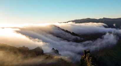Pilvet liikkuvat vuoriston yllä auringonnousun tai -laskun aikaan. (Tekoälyn luoma teksti)