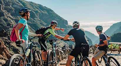 Ryhmä ihmisiä maastopyörien kanssa katselee luonnonkaunista näkymää vuorien ja vihreiden laaksojen välillä. (Tekoälyn luoma teksti)