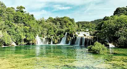 Luonnonkaunis vesiputous vehreän kasvillisuuden ympäröimänä. (Tekoälyn luoma teksti)