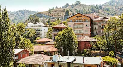 Kokoelma asuinrakennuksia puiden keskellä rinteen varrella. (Tekoälyn luoma teksti)