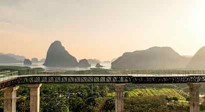 Sillan pylväät johtavat vesialueelle, taustalla vuoria. (Tekoälyn luoma teksti)