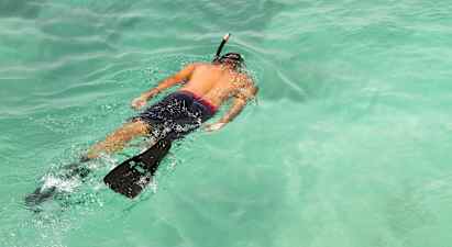 Henkilö snorklaa kirkkaassa turkoosissa vedessä. (Tekoälyn luoma teksti)