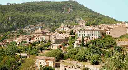 Kuva vuoristokylästä, jossa on useita kivitaloja vehreän kasvillisuuden ympäröimänä. (Tekoälyn luoma teksti)