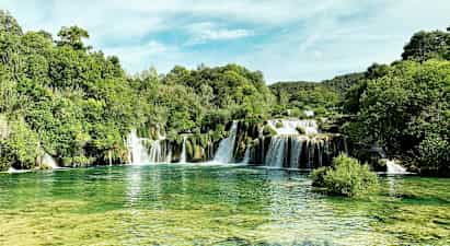 Luonnonkaunis vesiputous vehreän kasvillisuuden ympäröimänä. (Tekoälyn luoma teksti)