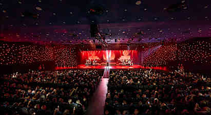 Konserttisali, jossa valaistulla lavalla esiintyy muusikoita yleisön edessä. (Tekoälyn luoma teksti)