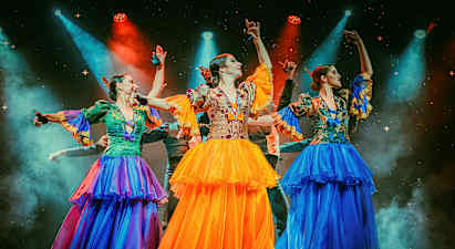 Kolme henkilöä, joilla on värikkäät perinteiset asut, tanssivat valaistulla lavalla. (Tekoälyn luoma teksti)