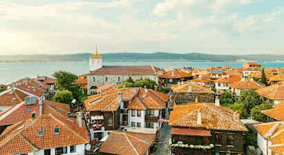 Vanhan kaupungin katot, taloja punaisilla tiilikatoilla ja kirkko taustalla meren lähellä rannikolla. (Tekoälyn luoma teksti)