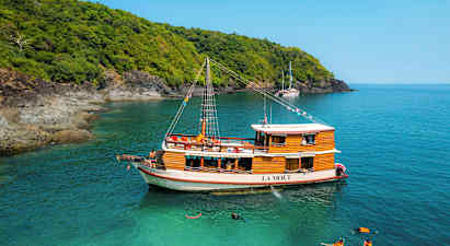 Puinen vene nimeltä La Moet on kiinnitetty turkoosiin veteen lähellä metsän reunustamaa rantaa. (Tekoälyn luoma teksti)