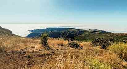Aurinkoinen vuorinäkymä pilvinen panorama ja kuiva kasvillisuus. (Tekoälyn luoma teksti)