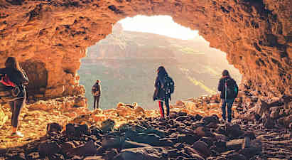 Ryhmä ihmisiä tutkii luolaa, josta on näkymä vuoristoiseen maisemaan. (Tekoälyn luoma teksti)