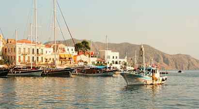 Satama, jossa on veneitä ja rakennuksia, taustalla näkyy vuoria. (Tekoälyn luoma teksti)