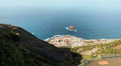 Näkymä rannikkokaupunkiin, taustalla meri ja kallio, nähtynä korkeuksista. (Tekoälyn luoma teksti)