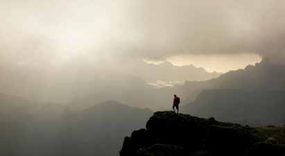 Vaeltaja seisoo vuoren huipulla, taustalla sumuisia laaksoja ja vuoria. (Tekoälyn luoma teksti)