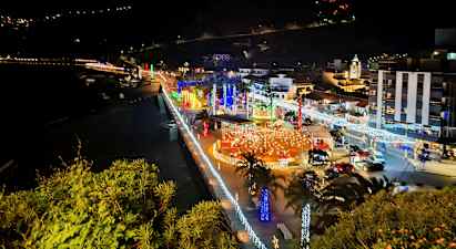 Kaupunki meren rannalla yöllä valaistuksineen ja koristeluineen. (Tekoälyn luoma teksti)