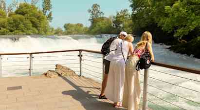 Kolme henkilöä nojaa kaiteeseen ja katsovat vesiputousta. (Tekoälyn luoma teksti)