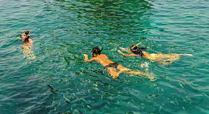 Henkilöt snorklaamassa kirkkaassa vedessä kalojen ympäröimänä. (Tekoälyn luoma teksti)