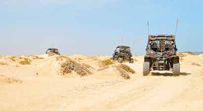 Kolme mönkijää ajaa hiekkadyyneillä autiomaassa. (Tekoälyn luoma teksti)