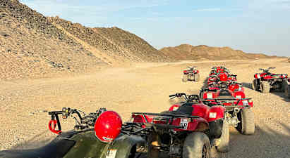 Jono mönkijöitä on pysäköity aavikkotielle, ympärillä hiekkaisia kukkuloita. (Tekoälyn luoma teksti)