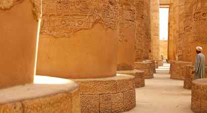 Kivipylväitä hieroglyfeillä historiallisessa rakennuksessa, yksi henkilö lähettyvillä. (Tekoälyn luoma teksti)