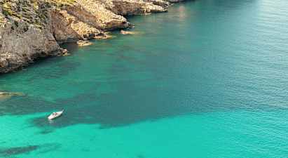 Vene ankkuroituu kirkkaassa turkoosissa vedessä lähellä kallioista rantaviivaa. (Tekoälyn luoma teksti)