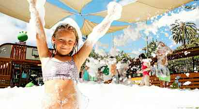 Ryhmä ihmisiä nauttii vaahtotoiminnasta ulkona katoksen alla. (Tekoälyn luoma teksti)