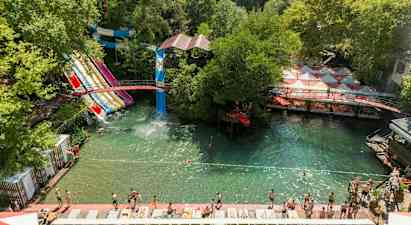 Vesipuisto, jossa on useita vesiliukumäkiä ja uintialue vehreyden ympäröimänä. (Tekoälyn luoma teksti)