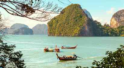 Pitkiä puuveneitä liikkuu vedessä, taustalla vihreitä vuoria. (Tekoälyn luoma teksti)