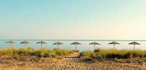 Ranta, jolla on seitsemän aurinkovarjoa rivissä ja taustalla meri. (Tekoälyn luoma teksti)