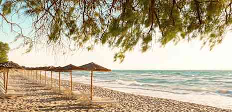 Hiekkaranta, jossa aurinkotuoleja ja aurinkovarjoja meren äärellä. (Tekoälyn luoma teksti)