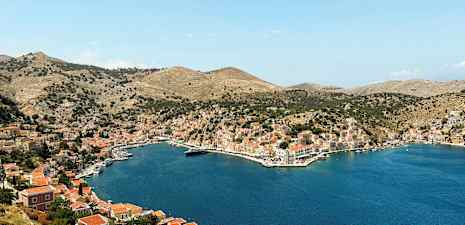 Kuva lahdelta, jota ympäröivät kukkulat, joissa on taloja ja pieniä veneitä vedessä. (Tekoälyn luoma teksti)